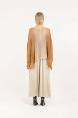 Poncho amplio de punto calado en mezcla de algodón y acrílico, con mangas regulables con jareta, degradé hecho a mano con aerógrafo, escote redondo, silueta oversize y largo a la cadera.