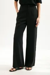 Pantalón de vestir color beige, de corte palazzo y tiro alto. Incluye cinturón de cadena plateada.