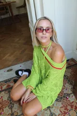 Vestido corto calado color terracota, con escote amplio y mangas largas. Incluye un accesorio tejido que puede usarse como collar o cinturón.