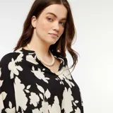 Blusa de manga larga con cuello en V, confeccionada en tejido ligero con estampado floral en blanco y negro.