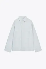 Sobrecamisa de algodón color celeste, con cuello solapa, manga larga con puño, bolsillos de plastrón en el pecho y bajo recto. Cierre frontal con botones ocultos por solapa.