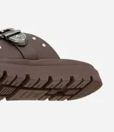 Sandalia plana negra con dos tiras anchas sobre el empeine, una con hebilla metálica estilo western y tachas plateadas.