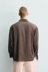 Camisa de corte relajado confeccionada en tejido fluido con mezcla de cupro, de manga larga con puños abotonados y cierre frontal de botones.