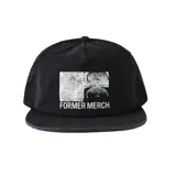 Gorro tipo trucker negro con paneles frontales de tela y paneles traseros de malla. Presenta un parche frontal blanco con un diseño gráfico abstracto dividido en cuatro secciones y el texto "FORMER MERCH" debajo.