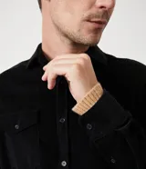 Camisa de hombre color verde oscuro, confeccionada en terciopelo, con cuello clásico, manga larga y dos bolsillos frontales con solapa y botón. Cierre frontal con botones.