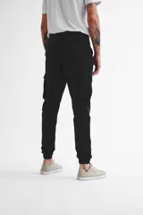 Pantalón cargo negro de gabardina con puños elásticos en los tobillos y múltiples bolsillos.