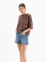 Short de denim azul de tiro medio-alto y silueta relajada, con lavado celeste claro, desgastados suaves y ruedo con acabado al corte.