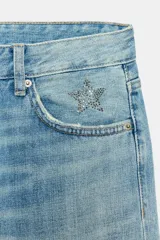 Jeans de tiro bajo y cinco bolsillos, con diseño de pierna ancha y larga, de color celeste con efecto desgastado. Cuenta con detalle de estrella bordada con brillos en el bolsillo delantero.