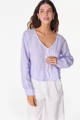 Camisa blanca de lino italiano, de manga larga, escote en V y cierre frontal con múltiples botones y detalles de alforzas.