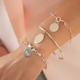 Brazalete tipo esclava de alambre redondo en plata 925, con dije de medalla circular colgante.