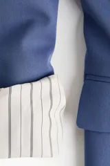 Blazer de sarga color azul, sin cierre, con solapas de pico, bolsillos delanteros con solapa y mangas largas.