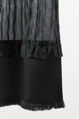 Vestido midi negro confeccionado en mezcla de viscosa con tejido satinado y efecto arrugado. Presenta escote en pico, tirantes finos ajustables, bajo con aplicación a tono y acabados deshilachados.