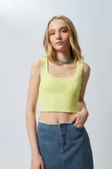 Top amarillo sin mangas con escote cuadrado, tejido de punto y costuras horizontales asimétricas en el frente.