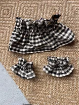 Cuellito y puños de tela con estampado de cuadros vichy en color negro y blanco, con diseño de volados en el borde.