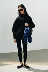 Zapato tipo bailarina deportiva de color negro, con suela de goma y detalle de lazo en la puntera redonda.