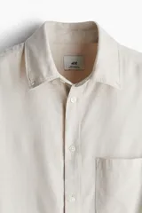 Camisa color crema de corte regular, con cuello abotonado, manga larga y bolsillo en el pecho.