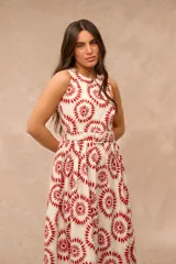 Vestido midi sin mangas, con cuello redondo y diseño estampado en tonos rojos y beige sobre base blanca. Incluye un cinturón ajustable de la misma tela en la cintura y falda con vuelo.