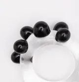 Anillo artesanal de vidrio transparente con diseño irregular, decorado con esferas de vidrio negro aplicadas en un lateral.