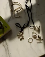 Collar con dije de bronce macizo con forma orgánica irregular, similar a un coral, suspendido de un cordón negro de seda natural anudado.