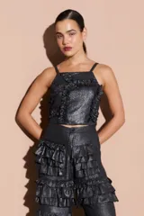 Top negro brillante con tirantes finos y volados en el frente.