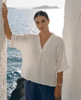 Blusa de lino color blanco, con cuello camisero y escote en V profundo, mangas 3/4 y corte holgado.
