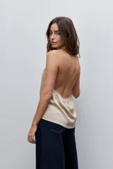 Top negro de cuello drapeado con diseño de espalda descubierta y calce fluido.