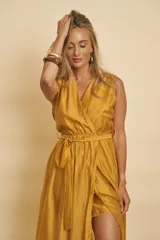 Vestido largo sin mangas color mostaza, con diseño cruzado tipo sobre, escote en V y lazo ajustable en la cintura.