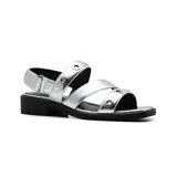 Sandalias plateadas con tiras horizontales y verticales, con detalles de ojales metálicos. Tiene una tira trasera con hebilla y un pequeño taco cuadrado negro.