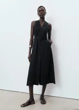 Vestido midi negro sin mangas, con cuello en V, cierre frontal con botones y cinturón ajustable del mismo tejido. Diseño evasé con mezcla de lyocell y lino.