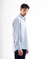 Camisa de vestir de corte clásico y manga larga, en color celeste claro. Presenta cuello camisero, cierre frontal con botones y un bolsillo abierto en el lado izquierdo del pecho.
