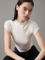 Remera de punto de viscosa elástica color blanco, con textura de canalé irregular, corte slim, cuello perkins y mangas raglán cortas.