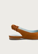 Ballerinas destalonadas de gamuza color camel, con suela plana, puntera redondeada y tira elástica fruncida en el talón. Interior de cuero en color celeste.