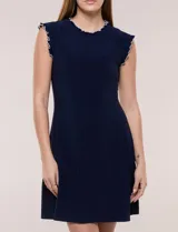 Vestido corto azul marino de seda fría elastizada, con escote redondo y sisas decorados con volados fruncidos en contraste de color blanco. Presenta corte entallado en la parte superior y falda acampanada.