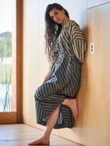 Vestido túnica gris con rayas verticales en tonos beige y negro, con lazo ajustable en la cintura.