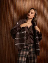 Buzo corto de tejido de punto en color negro, con diseño de textura en relieve y líneas horizontales blancas. Presenta cuello redondo y mangas largas con puños ajustados.