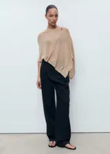 Poncho de tejido ligero y traslúcido en color beige, con diseño asimétrico y corte holgado.