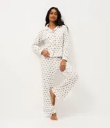 Pijama estilo americano de dos piezas confeccionado en plush. Incluye camisa de manga larga con cuello solapa y cierre frontal de botones, y pantalón largo con cintura elástica y cordón ajustable. Presenta un estampado geométrico de corazones sobre fondo claro.