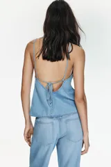 Top de denim con escote en pico, tirantes finos y diseño con lazada ajustable en la espalda.