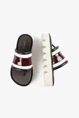 Sandalia con base alta y diseño de líneas audaces. Presenta capellada ancha con acabado brillante y estructura acolchada que aporta confort al andar. La suela dentada le da un carácter urbano y moderno, sin resignar comodidad.