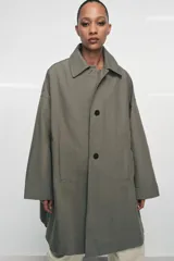 Trench oversize de Zara Woman Collection, confeccionado en hilatura de algodón. Presenta cuello solapa, manga larga, bolsillos delanteros y cierre frontal con botones ocultos bajo solapa.