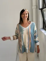 Sweater de punto con diseño abstracto de rayas verticales en tonos petróleo, beige y terracota. Presenta escote en V, corte holgado y mangas largas con puños vueltos.