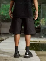 Bermuda negra de gabardina, corte ancho y largo, con bolsillos laterales.