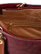 Cartera de mano de estructura rígida con textura símil cocodrilo en color bordó, con manijas superiores cortas en tono tostado y herrajes metálicos dorados.