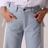 Pantalón de jean celeste con bolsillos traseros y laterales blancos.