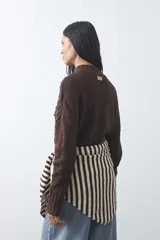 Polera de tejido de punto color marrón, con cuello alto y diseño de textura con relieves y trenzas. Posee mangas largas con puños acanalados.