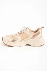 Zapatilla deportiva de mujer con plataforma gruesa, combinando paneles de malla transpirable color beige claro y superposiciones en tonos rosa viejo y crema. Cordones blancos y suela de goma color caramelo.