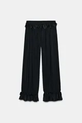 Pantalón bombacho negro, de tiro medio y cintura elástica, con detalle de encaje a tono en la cintura y bajo acabado en volante.