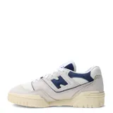 Championes urbanos New Balance modelo 550, con diseño de corte bajo inspirado en el básquet. Presentan una combinación de cuero y malla en tonos beige y azul marino, con suela de goma en tono crema envejecido.
