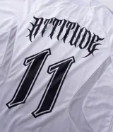 Remera de manga larga estilo deportivo con corte boxy, confeccionada en poliéster. Presenta cuello redondo, paneles laterales en tejido texturizado y estampados gráficos estilo tribal y lettering gótico en el frente.