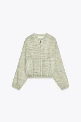 Cazadora de cuello redondo y manga larga, color verde claro con patrón a cuadros. Confeccionada en tejido de organza con estructura y acabados elásticos. Cierre frontal con cremallera y bolsillos delanteros.